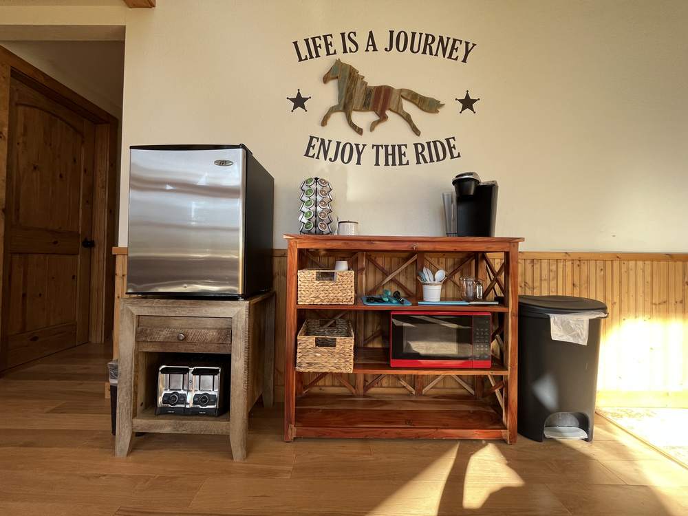 The in-cabin coffee bar with kettle, mugs and supplies beneath a “Life is a Journey” sign