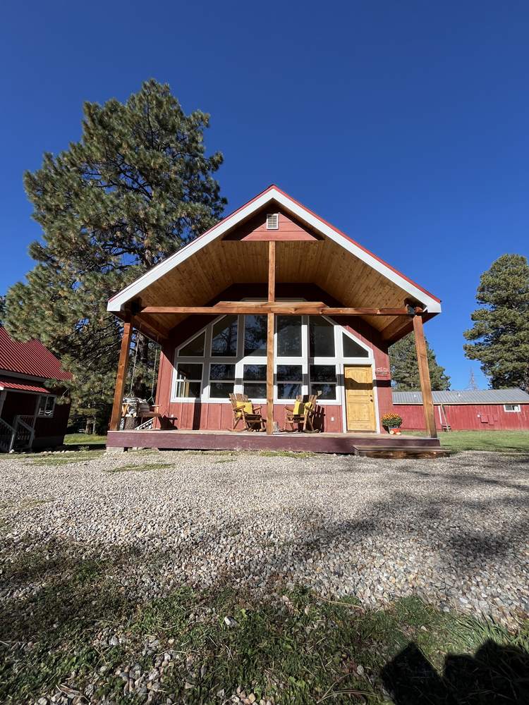 The A-frame cabin with its tall window wall under a blue Colorado sky