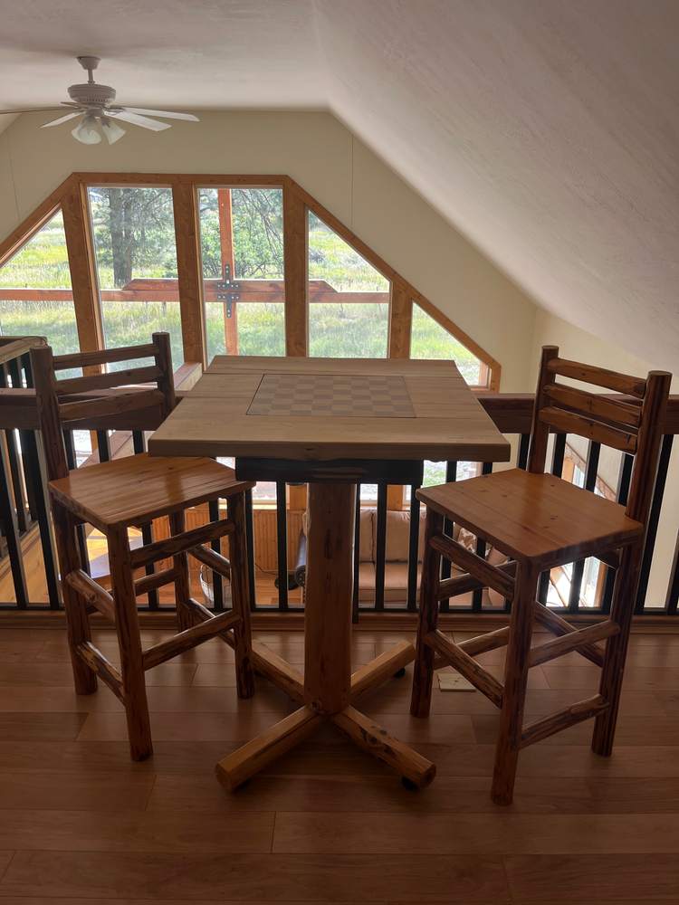 Loft dining nook with pub table under big gable windows