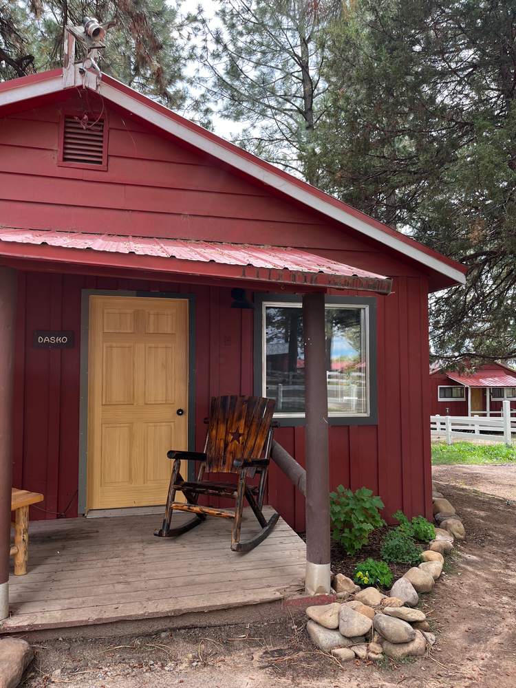A red guest cabin with a rocking chair waiting on the porch