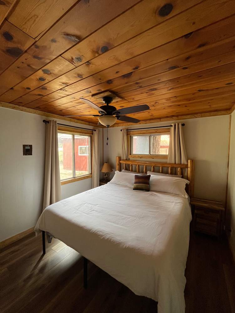 King bedroom under a knotty-pine ceiling