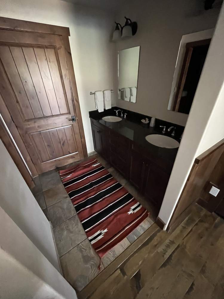 Suite bathroom vanity with double sinks and a striped rug