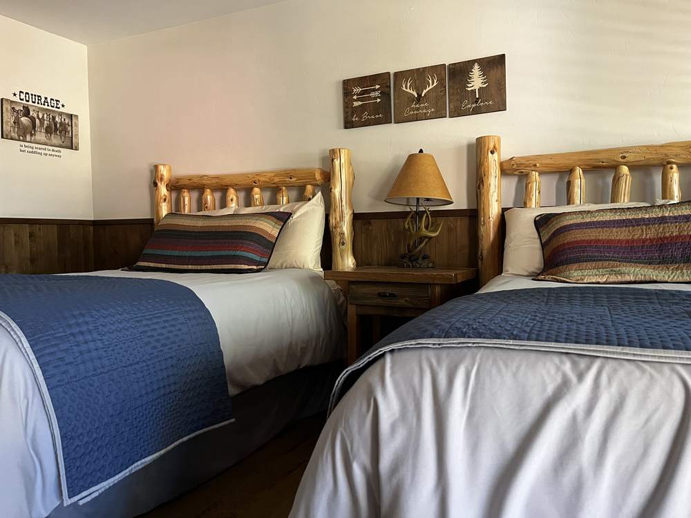 Two queen beds with log headboards and western blankets in the Double Queen Suite