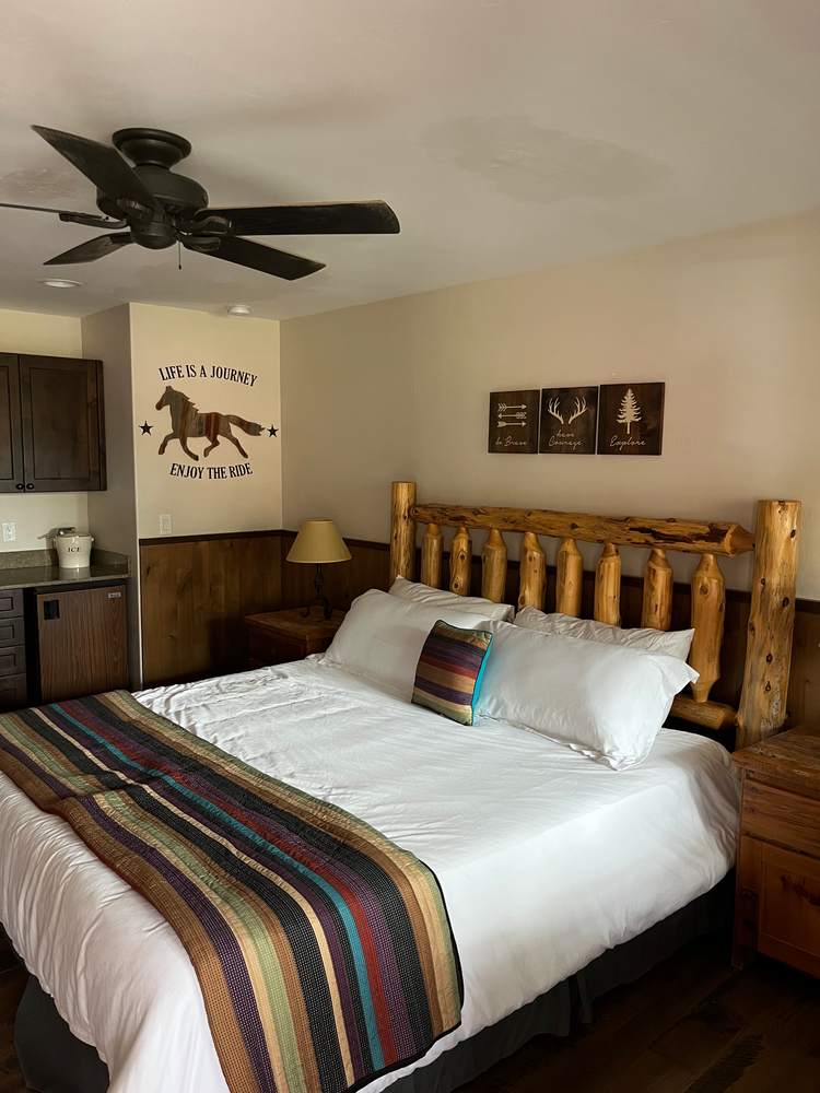 King Suite bed beneath western art and a ceiling fan
