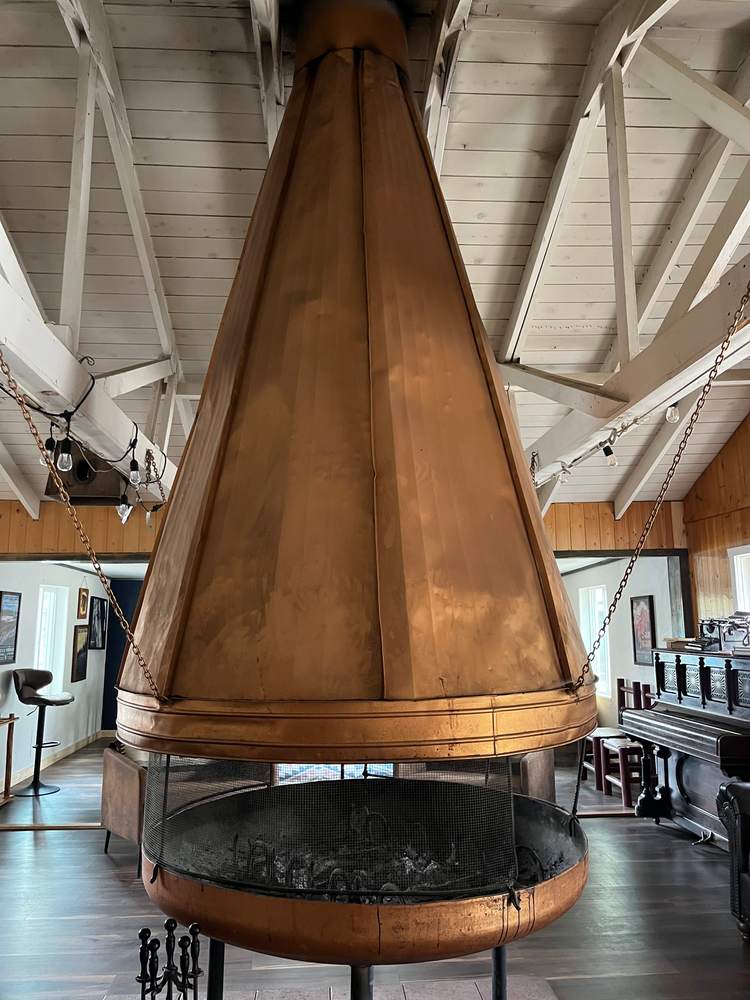 The lodge's copper cone fireplace beneath white timber trusses
