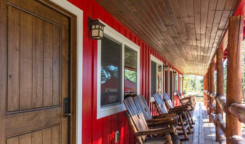 A long covered porch lined with handmade log rocking chairs