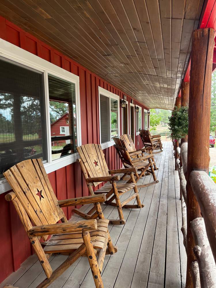 Handmade log rocking chairs lined along the lodge's red porch